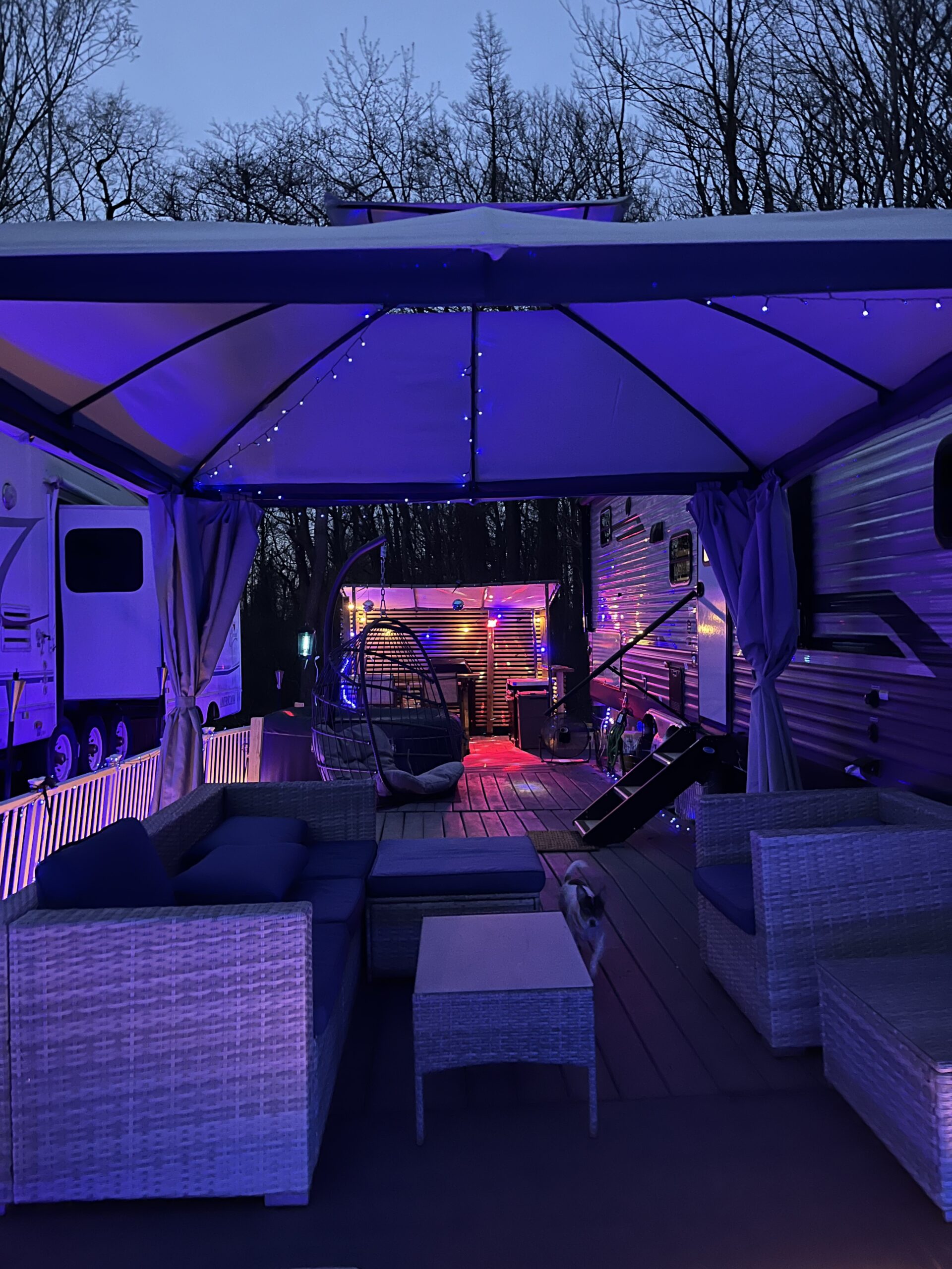 Deck at night with outdoor living room and kitchen in background