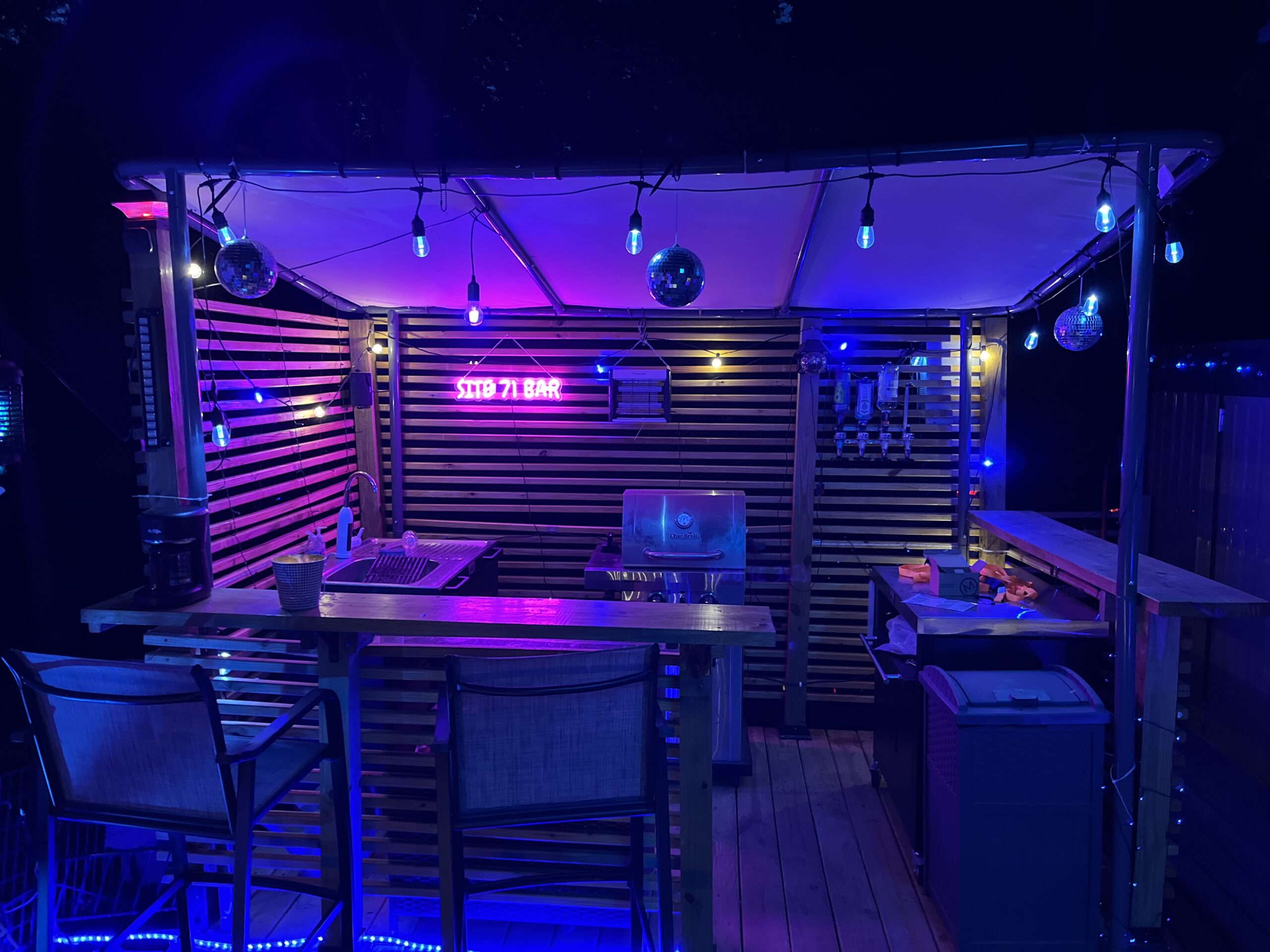 Outdoor kitchen and bar at night with illuminated sign